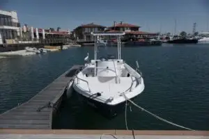 Яхти и рибарски лодки Yachts Nesebar. Лодката плаваща по време на живописен залез, с оранжеви отблясъци върху водната повърхност.